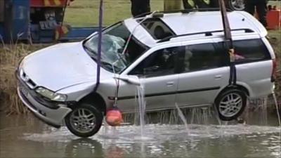 Car being lifted from water by crane