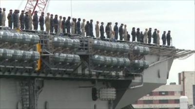 USS Bataan leaving port with people lined up on deck