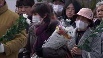 Relatives queue up with flowers at site of mass graves in Higashimatsushima