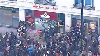 People breaking a glass window of a bank on Oxford Street in central London