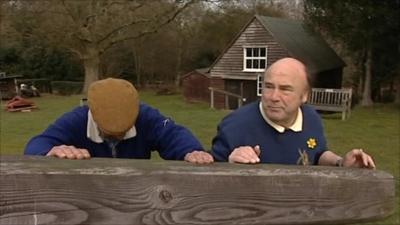 Two men pushing a wooden support for a windmill