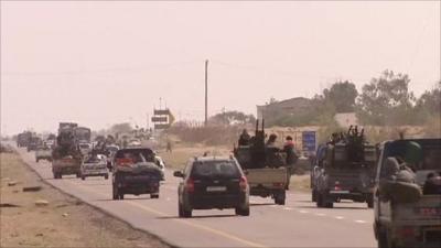 Rebel forces travelling along a road in cars and trucks