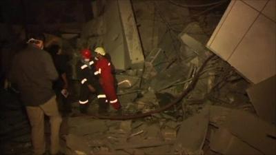 Rescue workers walk at site of Nato attacks in Tripoli