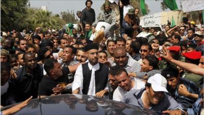 Saif al-Islam Gaddafi (c) in the crowd attending the funeral.