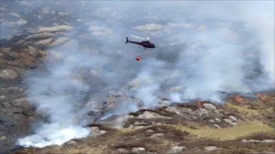 A helicopter drops water on a fire