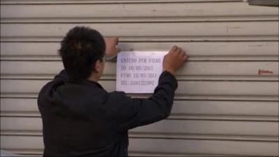 Man sticking up sign saying his shops is closed