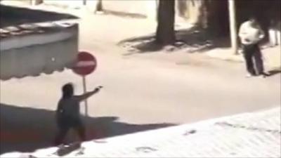 Man shooting a gun on a street in Hama, Syria