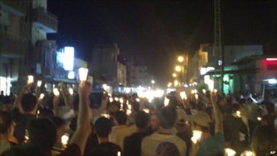 Anti-government protesters carry candles during a rally in the north-eastern city of Qamishli