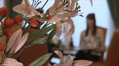 Woman out-of-focus behind flowers