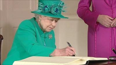 Queen signs visitors' book