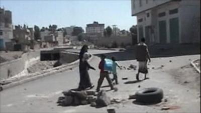 Family walk past rubble in Sanaa