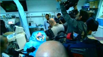 Injured child surrounded by cameras