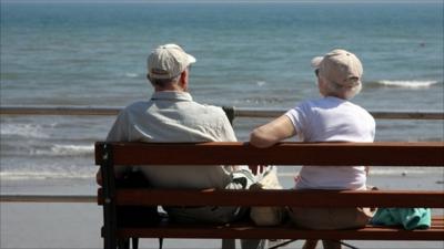 An elderly couple sitting on a beach