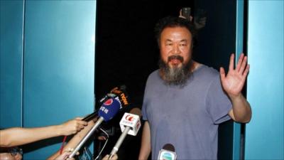 Ai Weiwei waves to the press from his studio but did not want to speak to the media