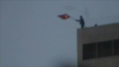 Syrian removing Turkish flag from roof of building in town near the border