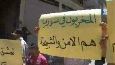 People hold up protest signs in Daraya, Syria