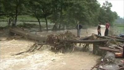 Men stand on a bridge above a flooded river in China