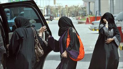 Saudi women get in the back seat of a car