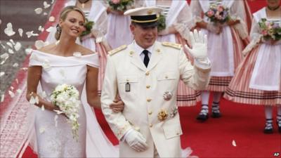 Prince Albert II waves to the crowd at the end of the religious ceremony, watched by his new wife, and Princess Charlene.