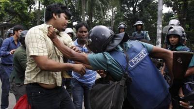 Bangladeshi policeman detains a protester in Dhaka