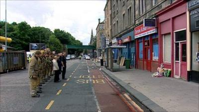 Colleagues of Ewan Williamson stand in a line with their heads bowed