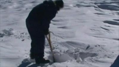 Rescue worker tries to dig through snow to reach stranded people