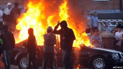 Masked youths in front of burning car