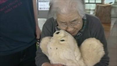 Woman cuddles robot seal