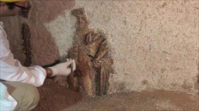 Archaeologist brushing dust from mosaic of Apollo