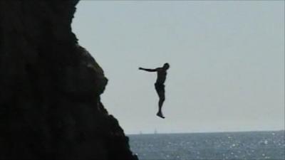 A person jumping off a cliff into water