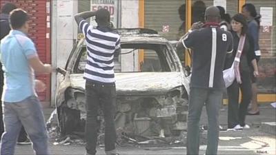 People taking photographs of a burnt-out car