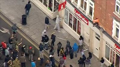 Hooded man attacking window of betting shop in Hackney