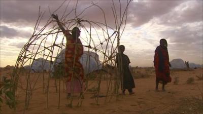 A mother in Kenya starts to build a frame for shelter near the refugee camp