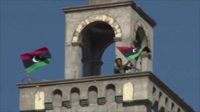 A rebel places a flag at the top of a mosque