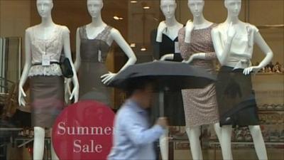 Consumer walking in rain past summer sales