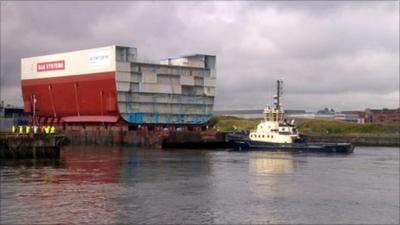 Aircraft carrier hull leaves the BAE shipyard on a barge