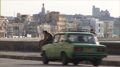 A Lada car drives through Havana seaside