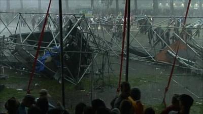 Festival-goers sheltering from rain in front of collapsed rigging towers