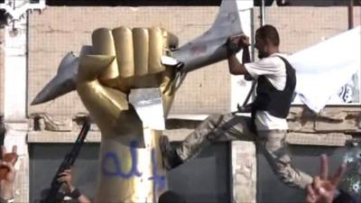 Rebels climb on statue in Gaddafi's compound