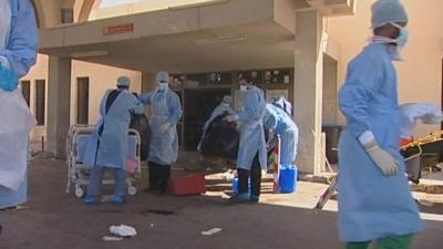 People wearing medical clothes clearing bodies from hospital