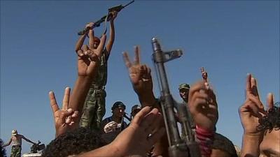 Rebel hold up their fingers in a peace sign in Libya