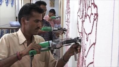 An Indian worker threads fabric onto a drape