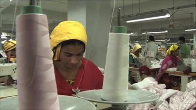 A woman stitches clothing at a garment factory in Bangladesh