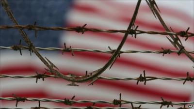 US flag can be seen (blurred) behind barbed wire at Guantanamo Bay