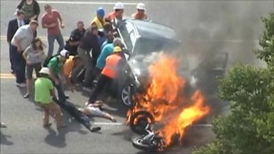 Passers-by lifting the car as the victim is pulled to safety