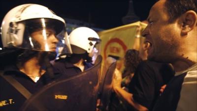 An anti-austerity protester shouts at police officers outside the Greek parliament