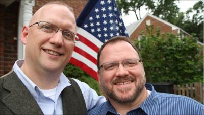 Gay soldier and partner in front of US flag