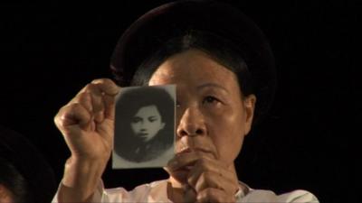 Vietnamese woman shows the picture of a relative who died in the war