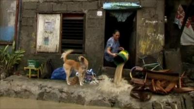 Woman in Philippines emptying water from her home