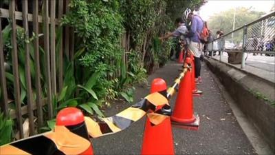 A row of cones and tape in front of the fence where radiation was found